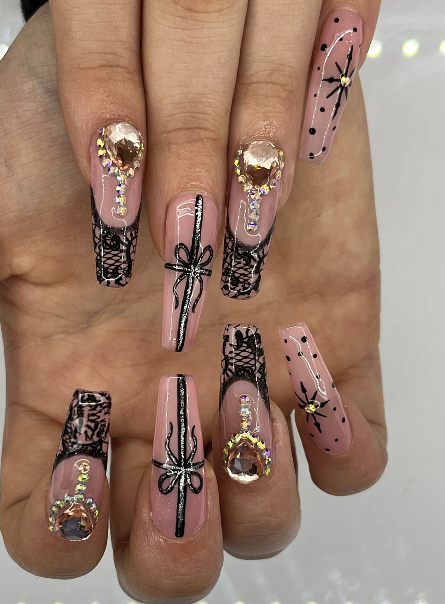 Nude coffin nails with black lace, bows and champagne gemstones