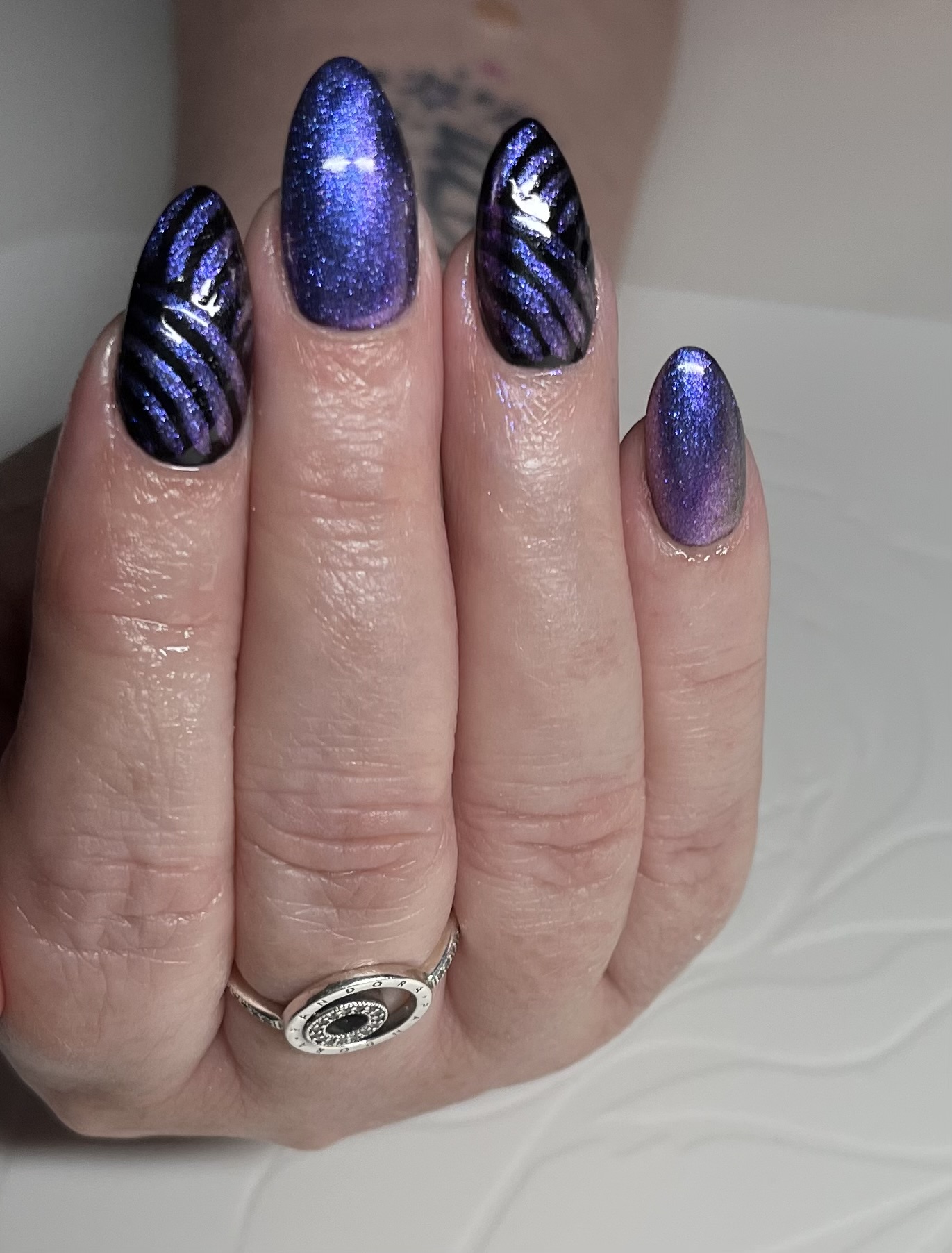 Almond nails with deep purple cat-eye shimmer and black tiger stripes